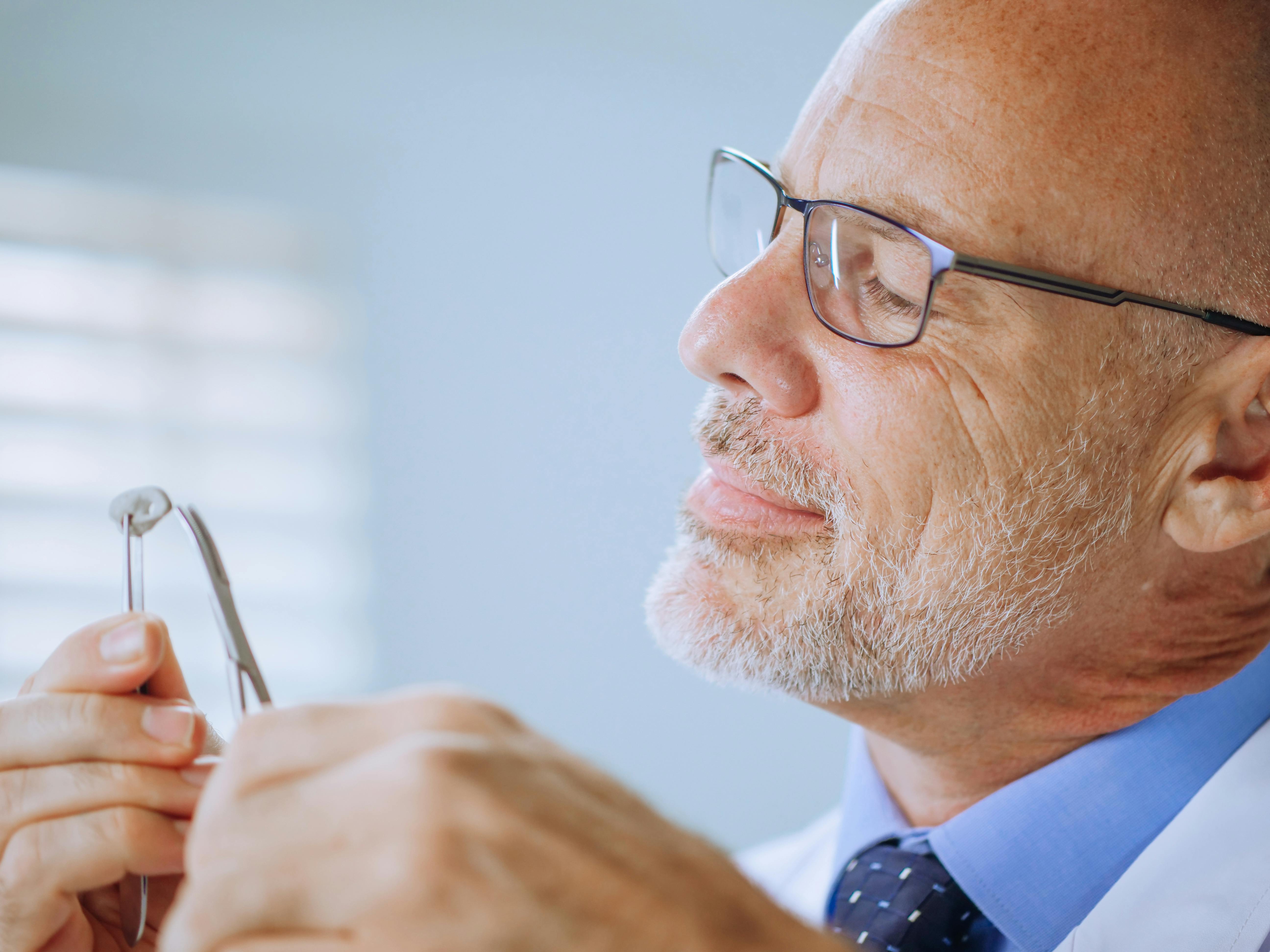 Audiologist examining a hearing aid with tweezers